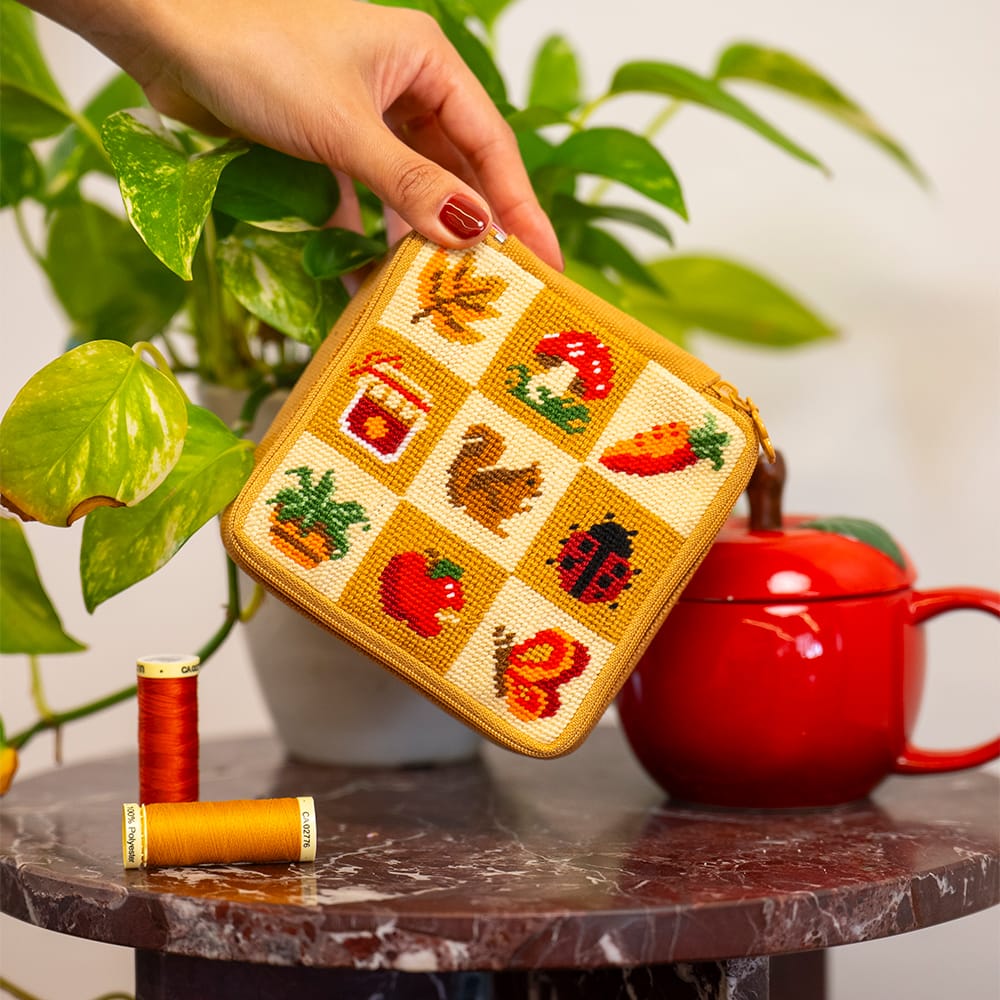 The finished FALL HARVEST CHARMS pouch held beside a red teapot and a pothos plant