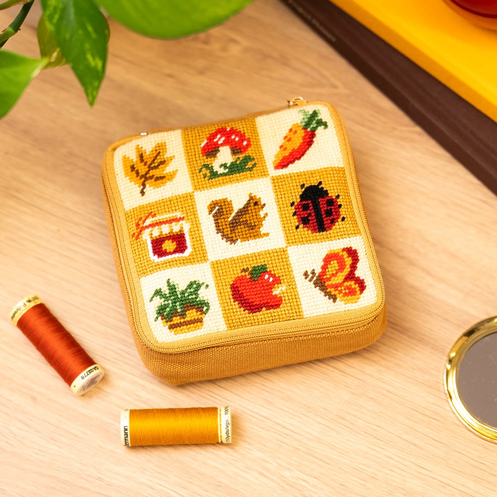 FALL HARVEST CHARMS finished pouch on a desk with thread spools and a gold pocket mirror