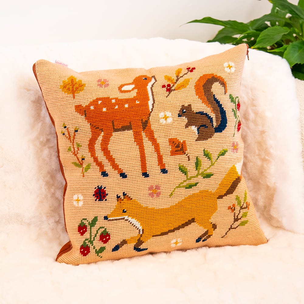 Finished FALL FRIENDS cushion: a deer, squirrel and fox with flowers and berries on tan