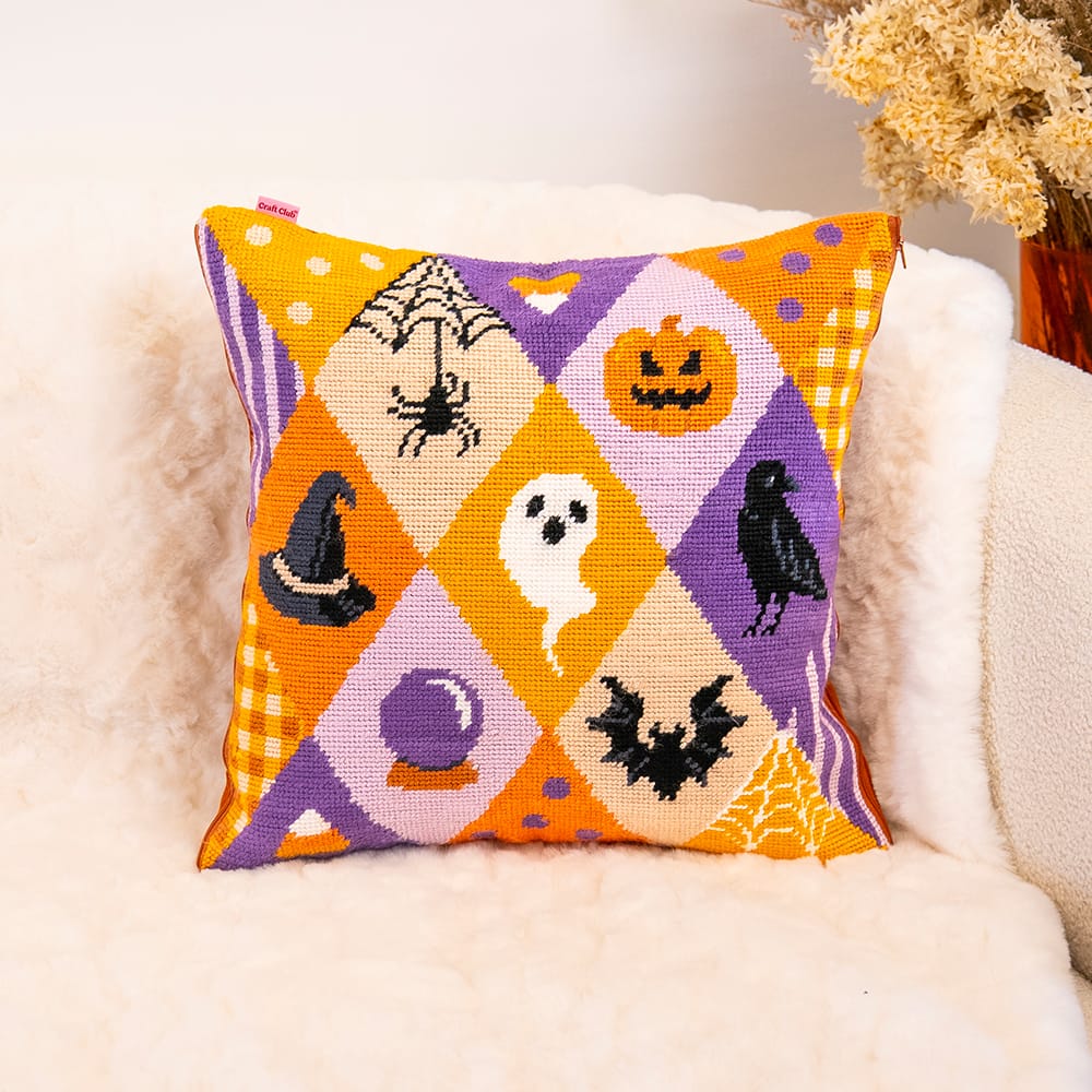 SPOOKY TROVES needlepoint cushion finished and styled on a cream sheepskin armchair