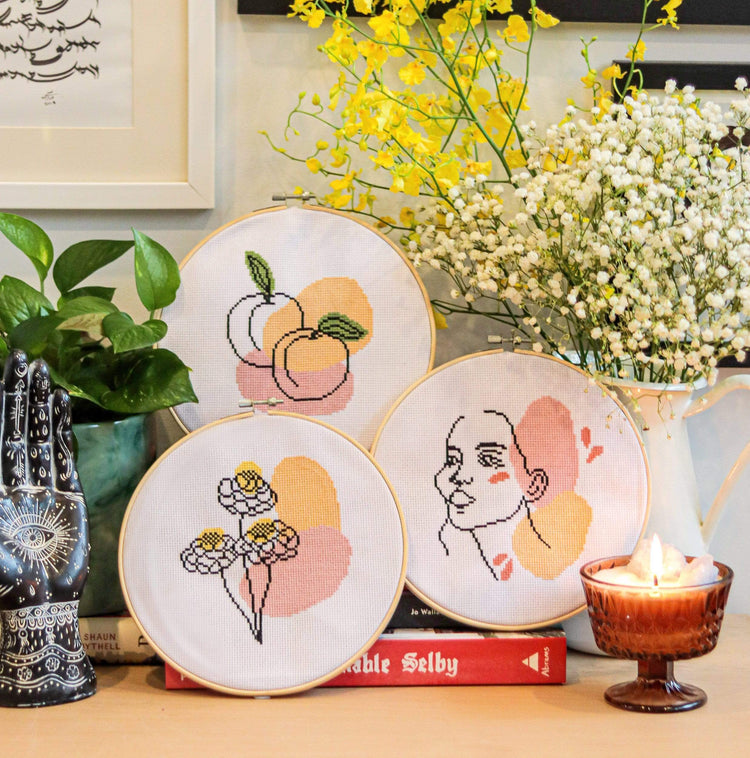 Craft Club Co BLOOM Cross Stitch Kit, Craft Club Co PEACHY Cross Stitch Kit, Craft Club Co LOVER Cross Stitch Kit. The three kits match to form a triptych, their organic shapes are in the same pink and orange colours.