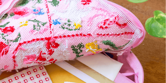 Love Letters Half Stitch Pouch is laying open, the contents and backing is on display.
