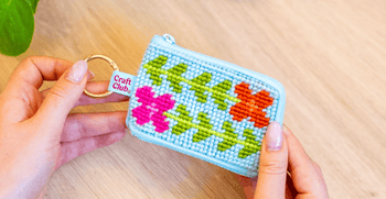 Nakisah holding a completed Beginner Blooms tapestry needlepoint kit