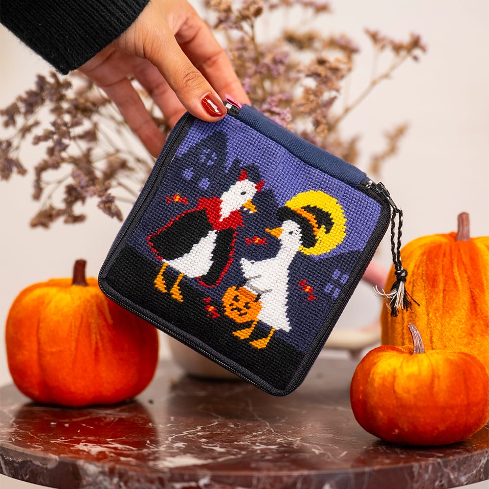 The finished TOIL AND TROUBLE pouch held beside two velvet pumpkins