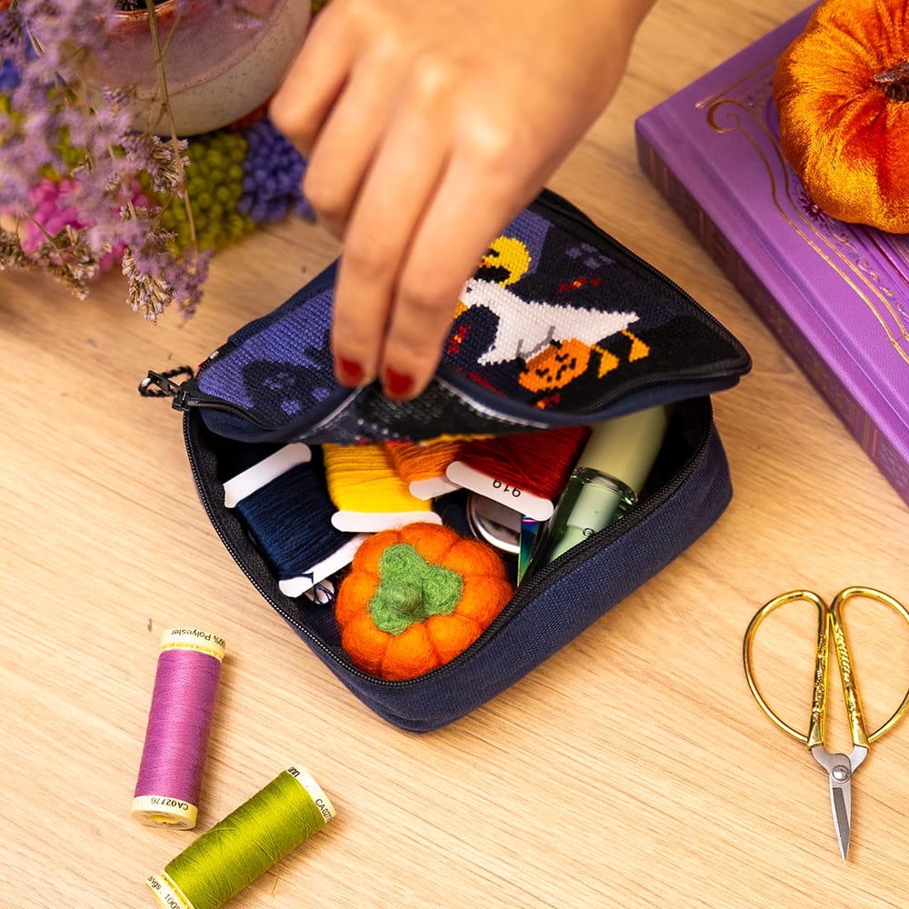 The TOIL AND TROUBLE pouch unzipped, showing craft supplies stored inside