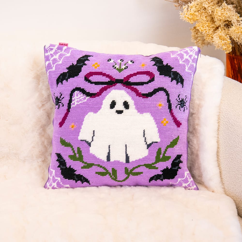 BOO-TIFUL ghost needlepoint cushion finished and styled on a cream sheepskin armchair