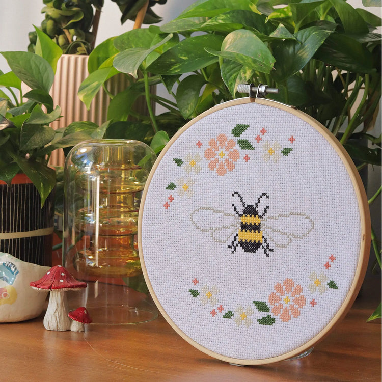 Craft Club Co BEE & BLOSSOM Cross Stitch Kit. The design from a side angle, showing pot plants and a decorative mushroom next to it.