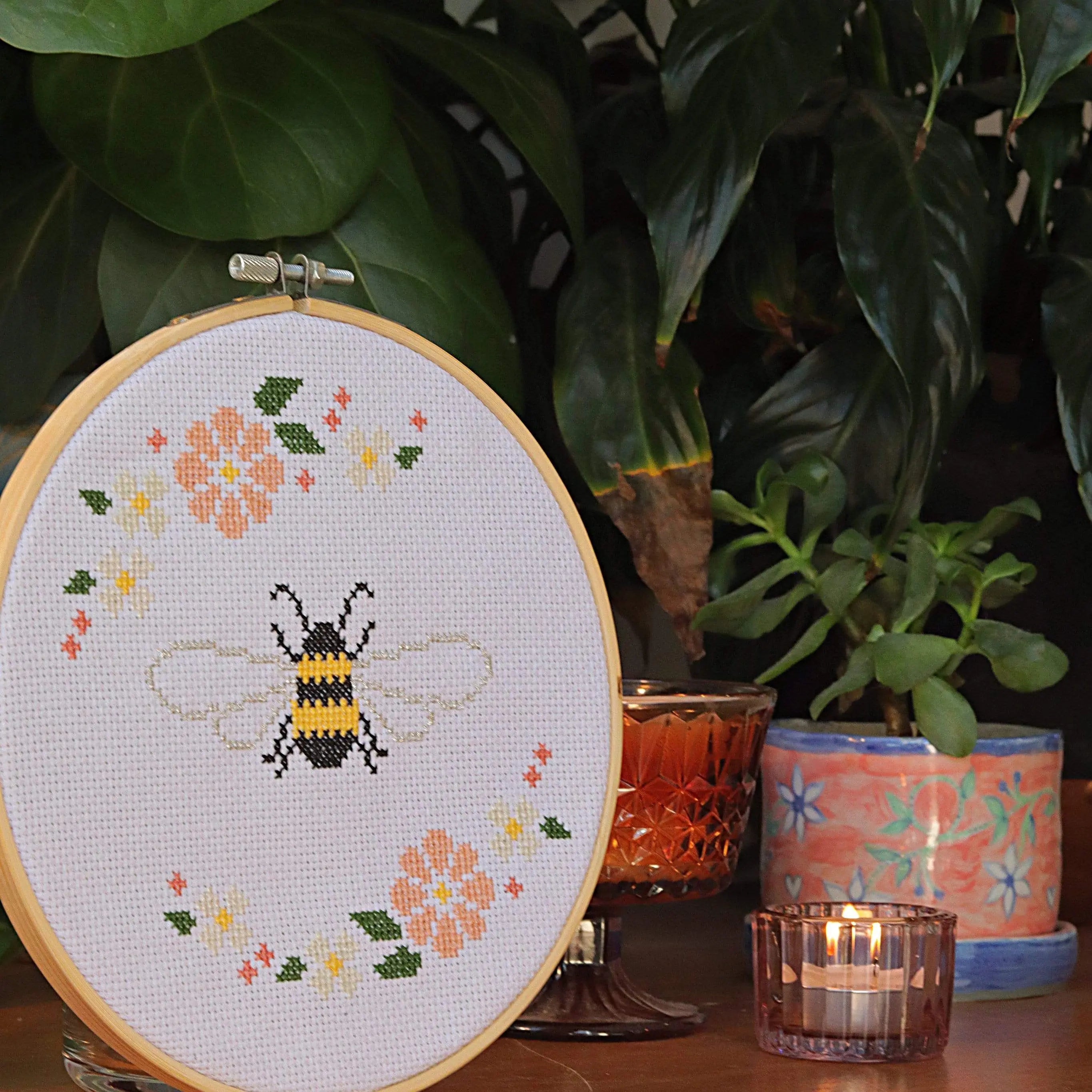 Craft Club Co BEE & BLOSSOM Cross Stitch Kit. Side view of the design, showing a candle and pot plant next to it.