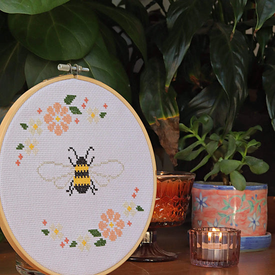 Craft Club Co BEE & BLOSSOM Cross Stitch Kit. Side view of the design, showing a candle and pot plant next to it.