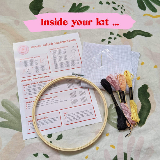 Craft Club Co BLOOM Cross Stitch Kit. Showing what is inside your kit, a bamboo hoop, instructions, aida fabric, full packs of thread and a needle.