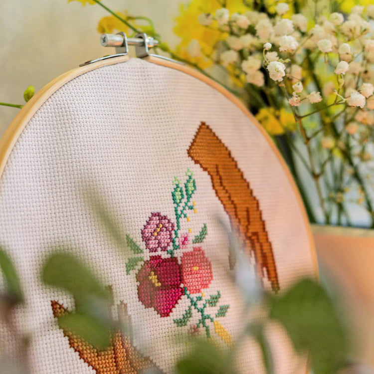 Craft Club Co HANDS HOLD Cross Stitch Kit. Close up of the design amongst white flowers. The detail of the stitches is shown.