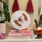 Craft Club Co HANDS HOLD Cross Stitch Kit. The design on a pink stack of books, with a candle and crystal next to it.