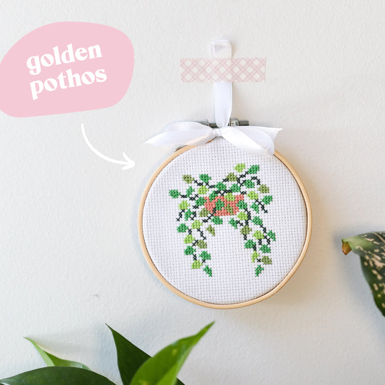Craft Club Co POT PLANT MINIS Cross Stitch Kit. A close up of the golden pothos design, with hanging leaves in three colours of thread and a pink pot.
